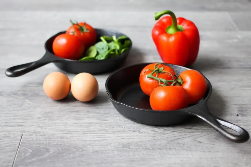 kleine pfannen mit tomaten, paprika, eiern und kräutern